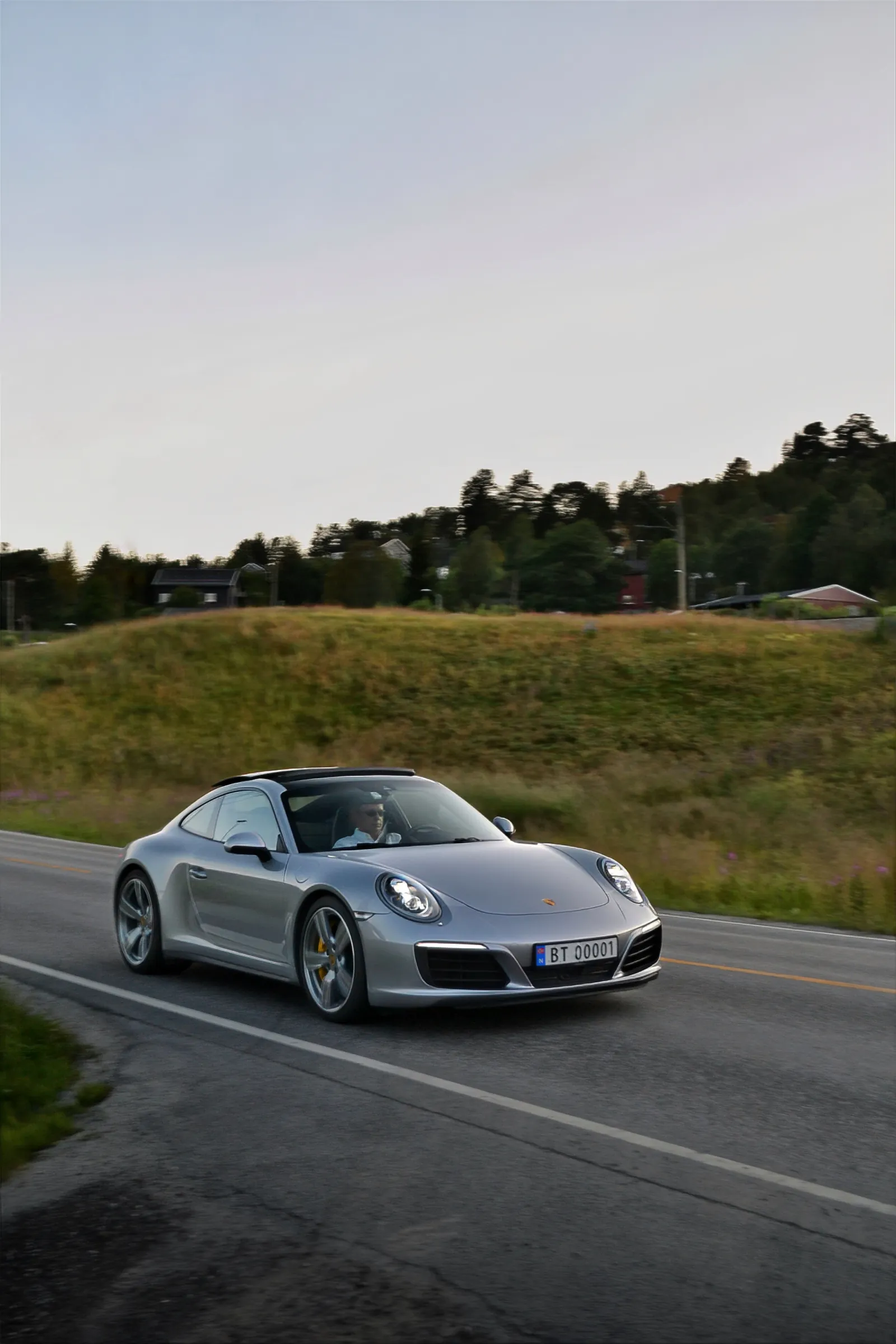 Silver Porsche 911 driving on a country road