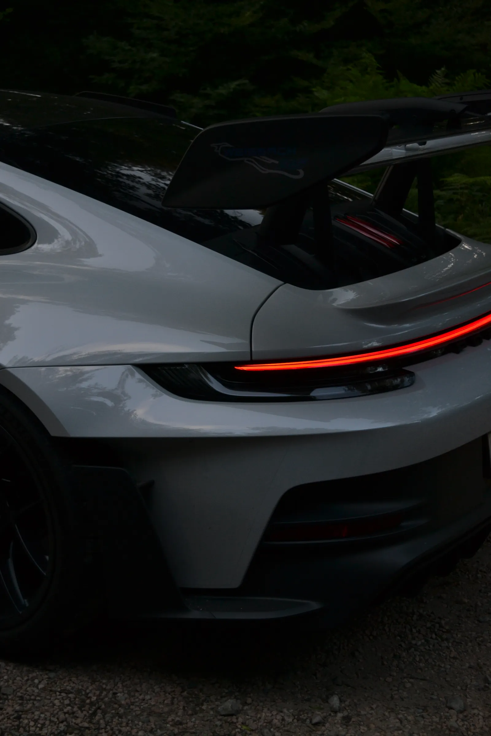 Rear of a grey Porsche 911 GT3 with raised wing and red light bar