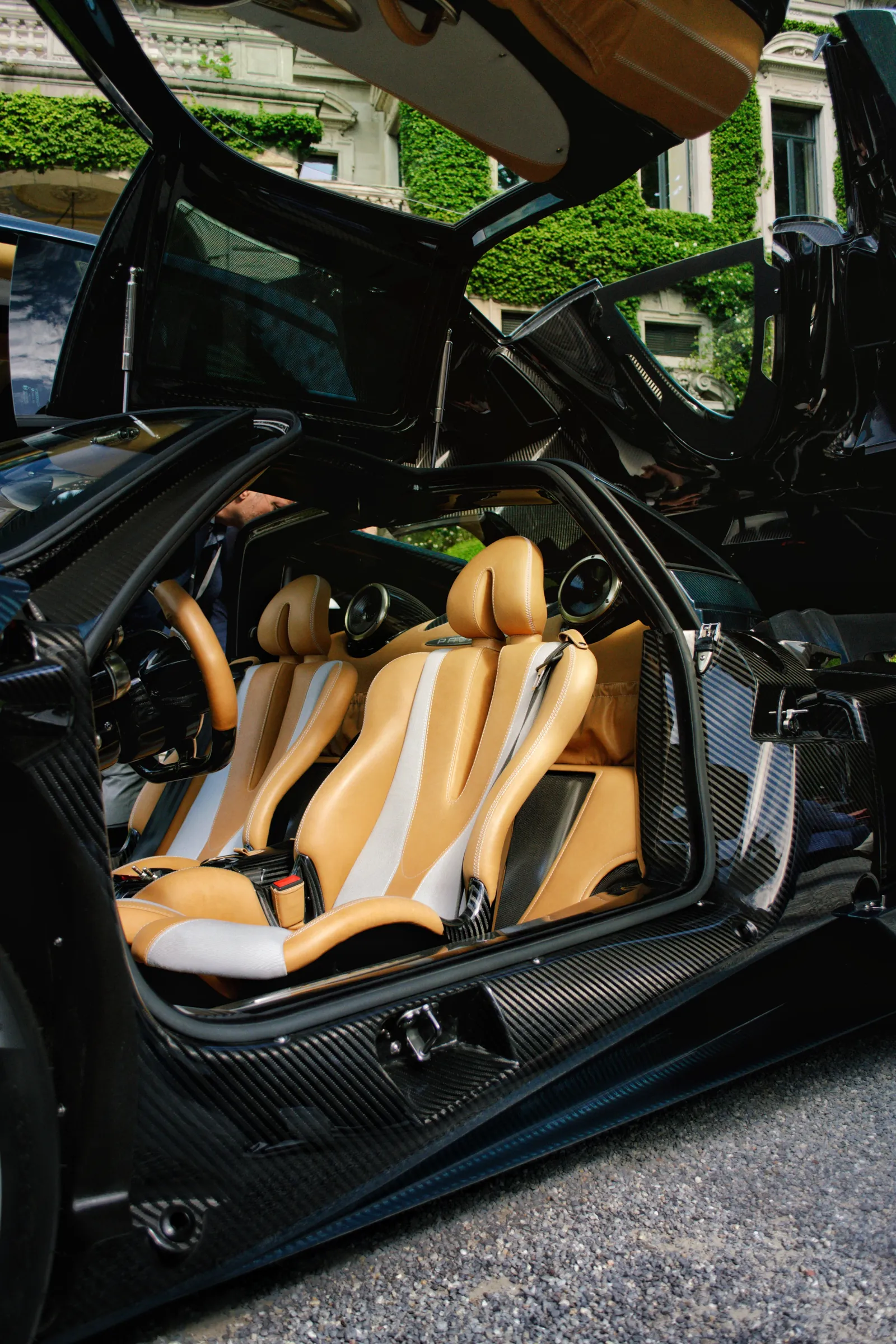 Open gullwing door showing the tan leather interior of a Pagani