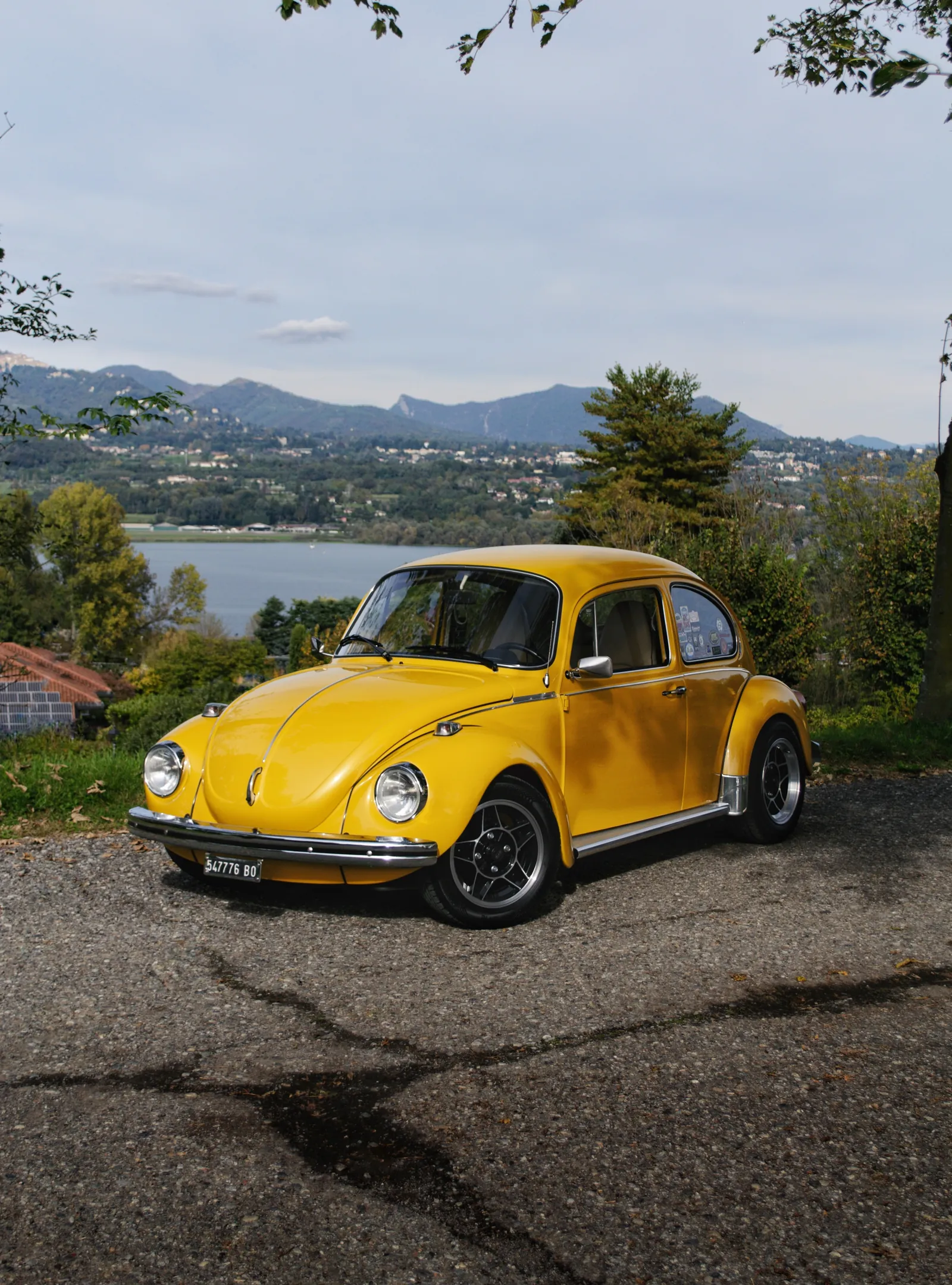 Yellow Volkswagen Beetle with a lake and mountains behind