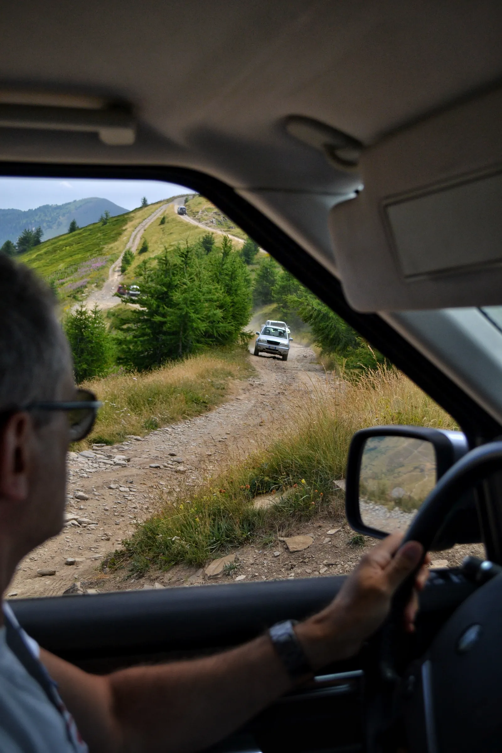 Driver's view through the window on a mountain dirt track with another 4x4 ahead