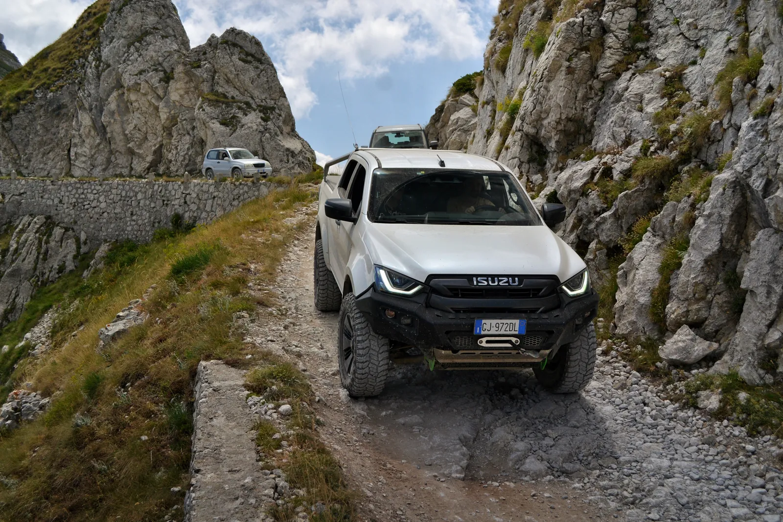 White Isuzu pickup on a rocky mountain track